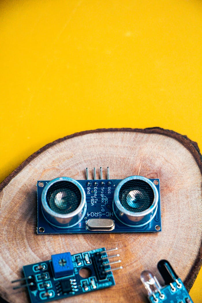 Close-up of electronic modules on a wooden slice against a vibrant yellow background.
